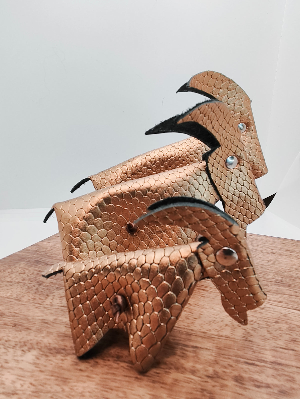 Vue rapprochée des trois chèvres en cuir doré, montrant leur texture à motif d’écailles