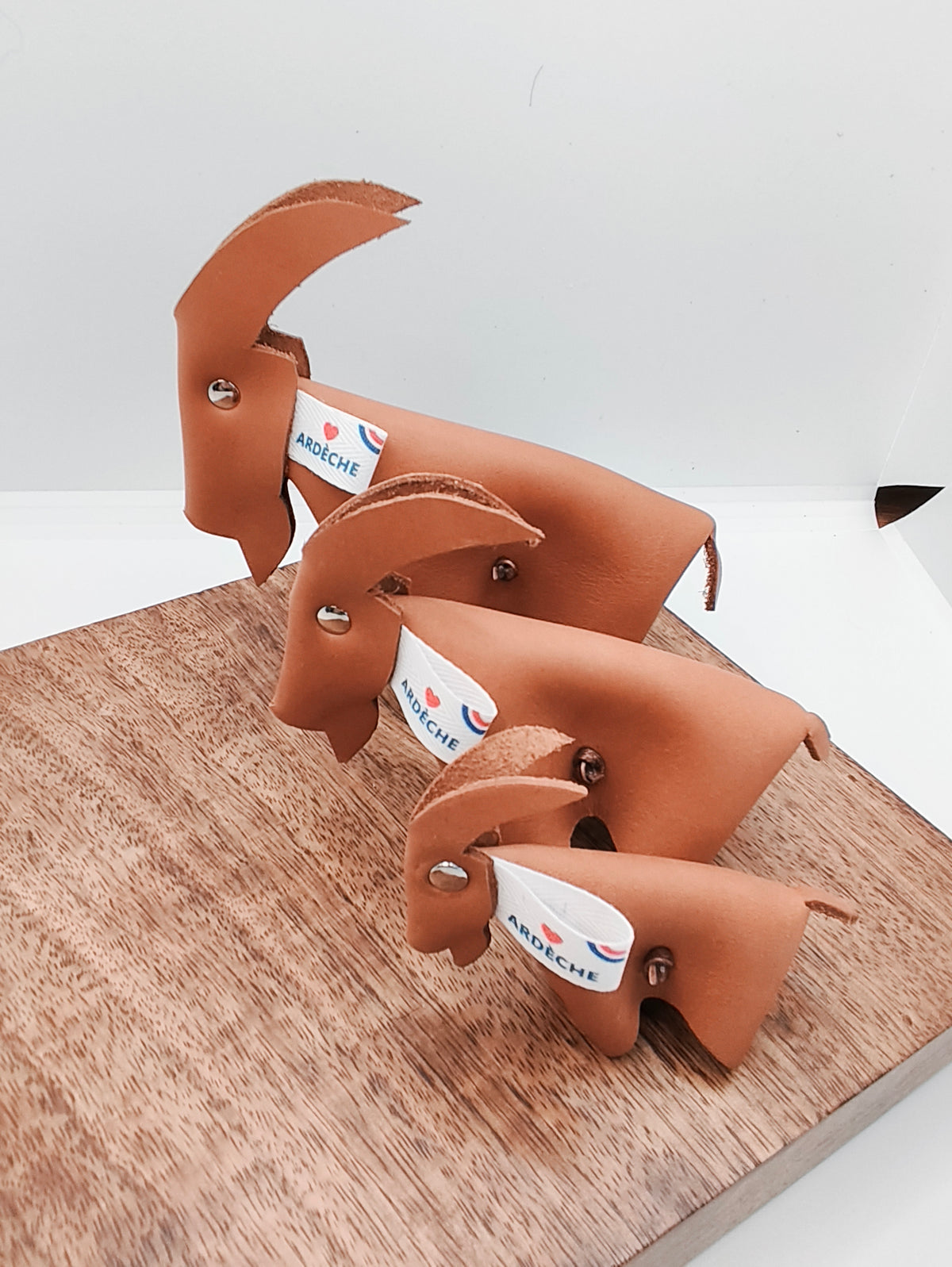 Trois chèvres décoratives en cuir camel lisse avec étiquettes Ardèche, alignées par taille