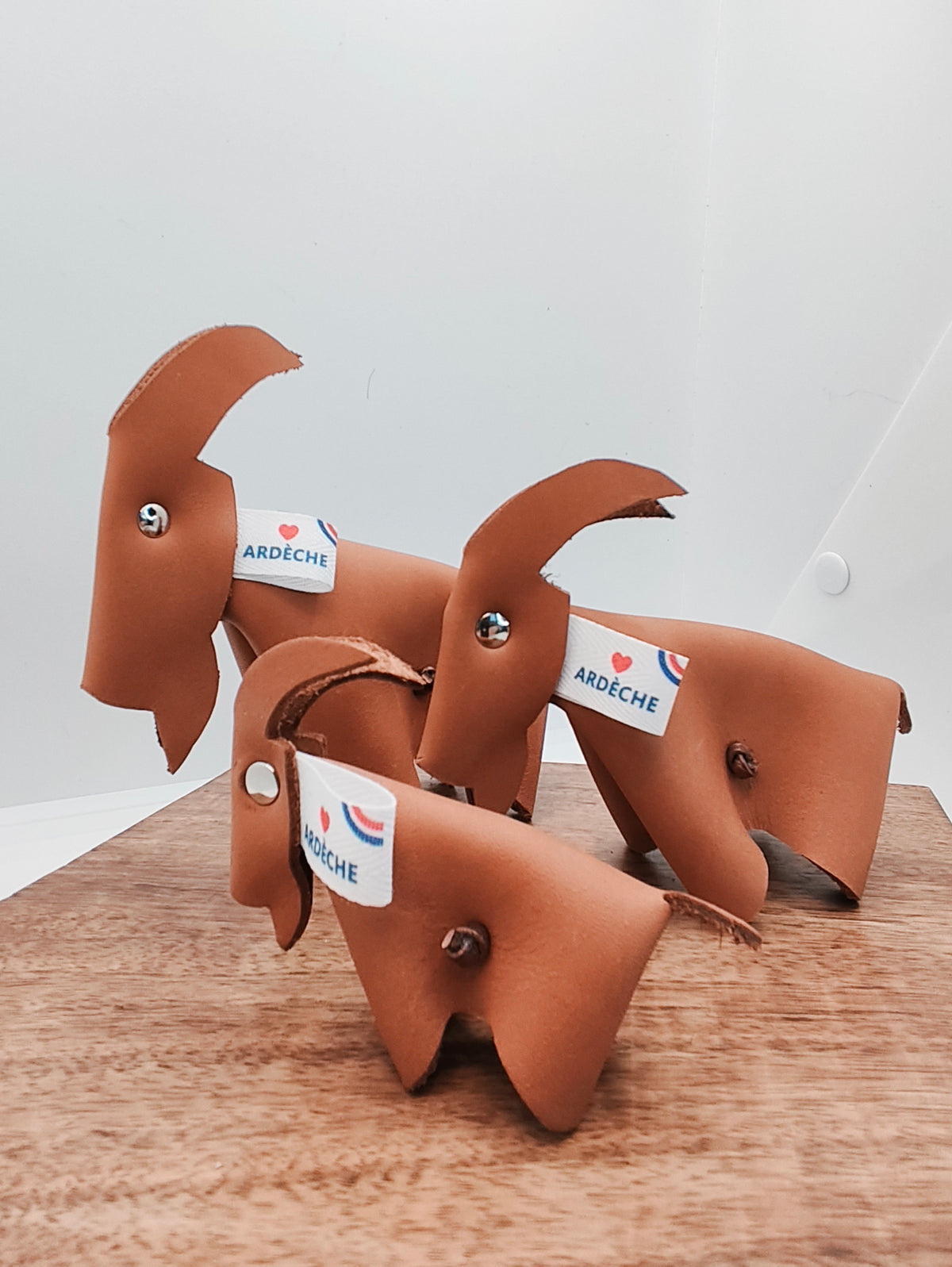 Trio de chèvres en cuir camel lisse avec étiquettes Ardèche, la petite chèvre au premier plan